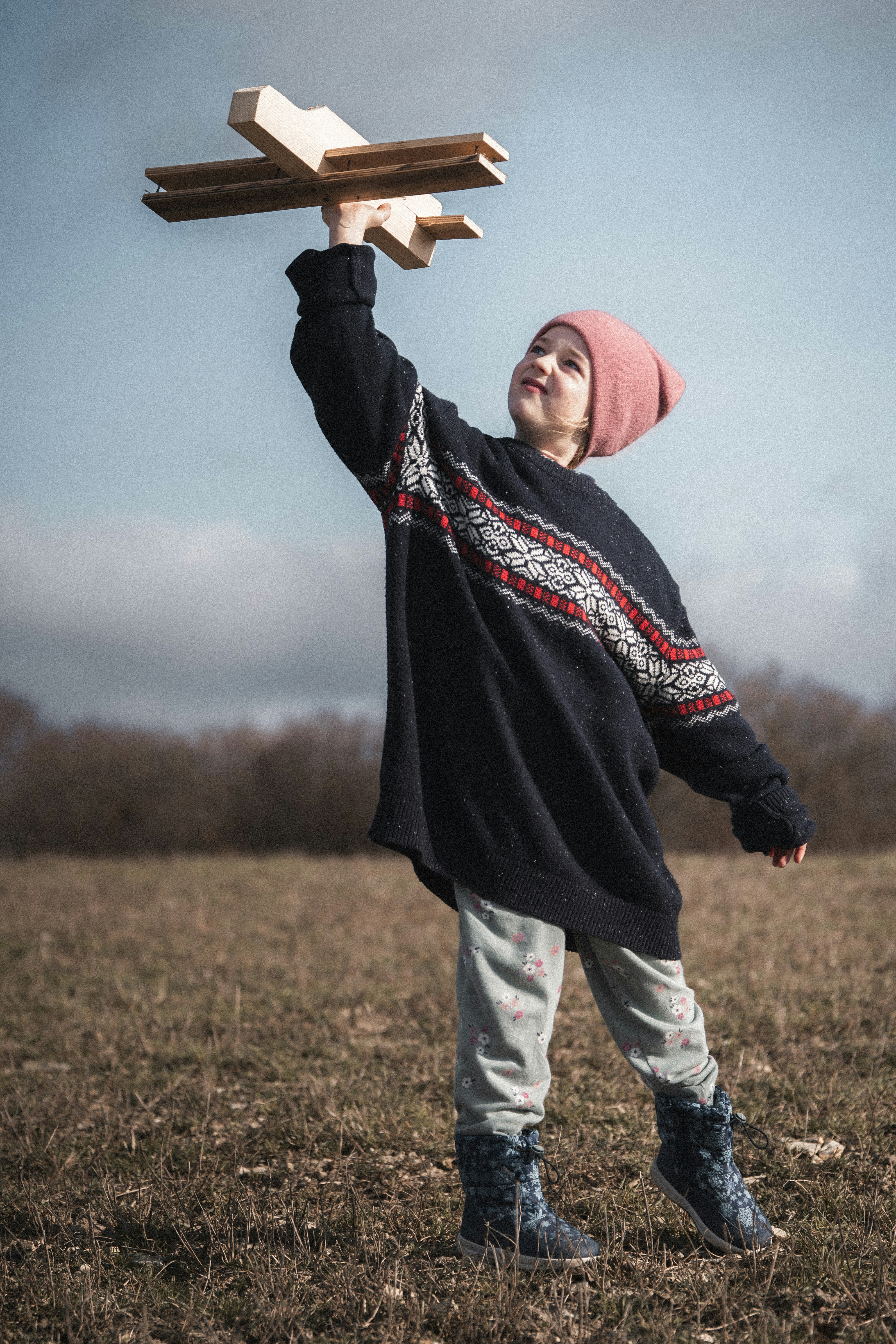 Chlid holding a model plane and reaching towards the sky